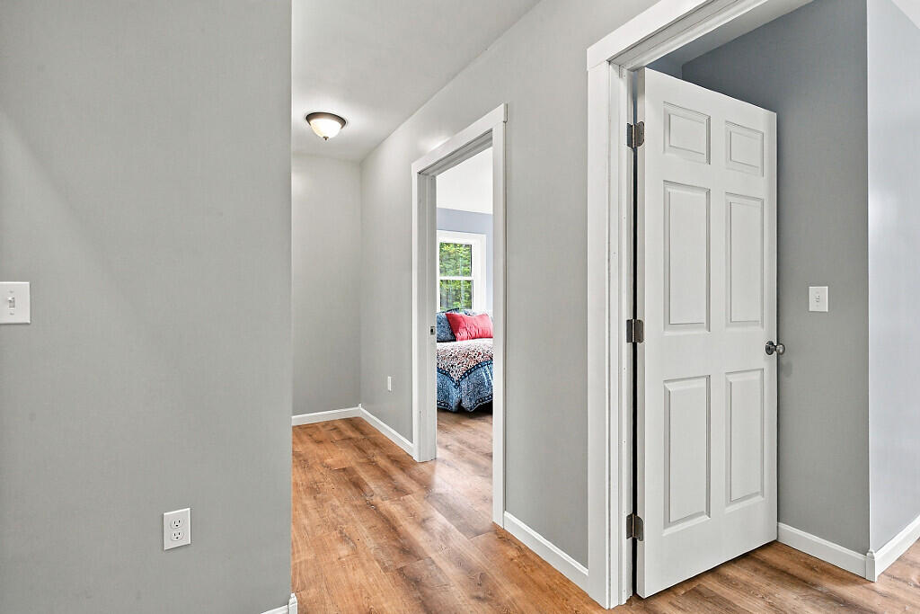 Hallway with hardwood floors and an open doorway to a furnished bedroom.