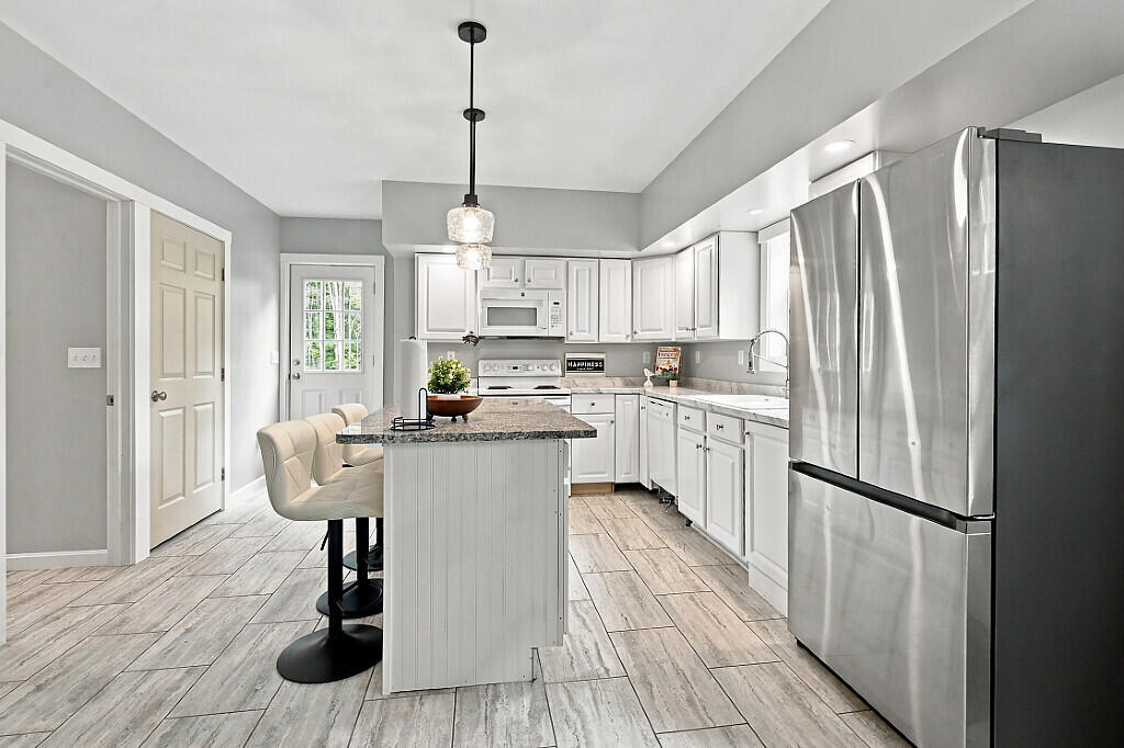 Kitchen with white cabinets, stainless steel appliances, and a dark stone island with seating.