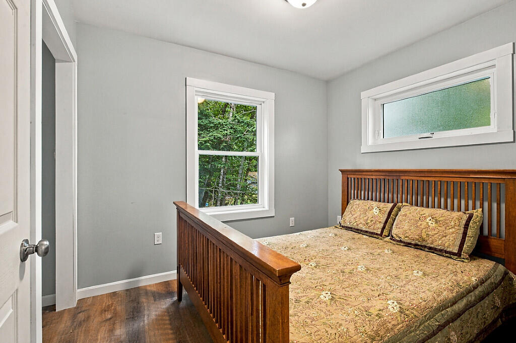 Bedroom with a wooden slat bed, floral bedding, gray walls, and two windows.