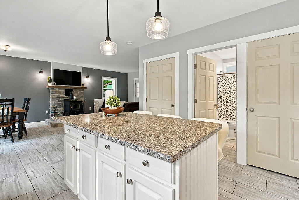 Open-plan kitchen with a large granite-topped island and stone fireplace in the adjoining living area.