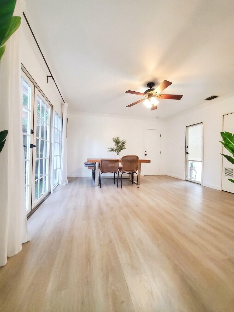 Bright dining room with pale wood floors, sliding glass doors, and a ceiling fan.