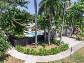 Tropical property grounds with a small pool behind a black fence and curved walkway.