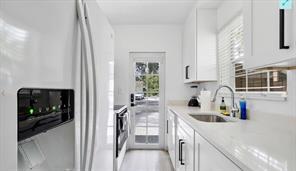 White kitchen with stainless steel appliances, a black built-in microwave, and a glass-paneled door.