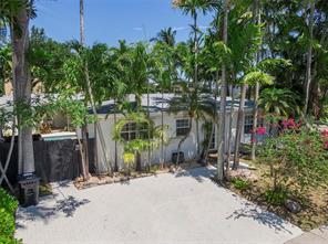 Property exterior with a broad paved entry area framed by palms and tropical landscaping.