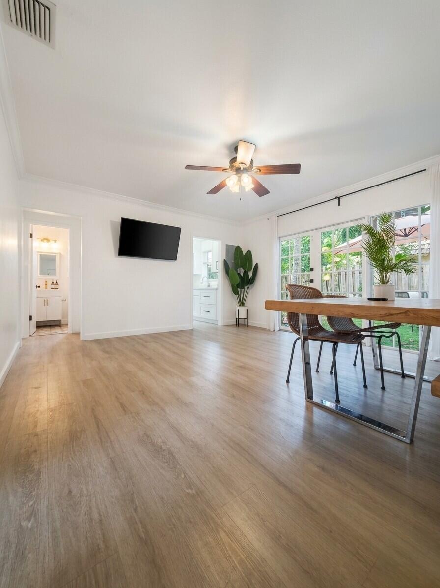 Dining area with light wood floors, a wooden table, and glass doors opening to a patio.