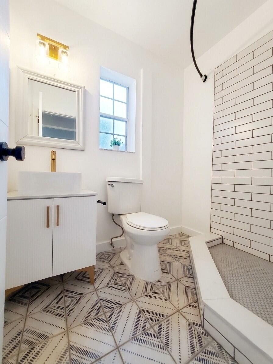 Bathroom with a vessel sink, geometric floor tiles, and a white subway-tile shower.