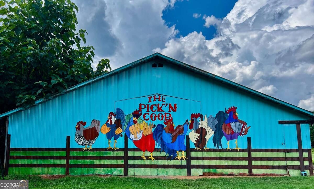 Turquoise barn with a colorful chicken mural and “THE PICK'N GOOD” lettering.