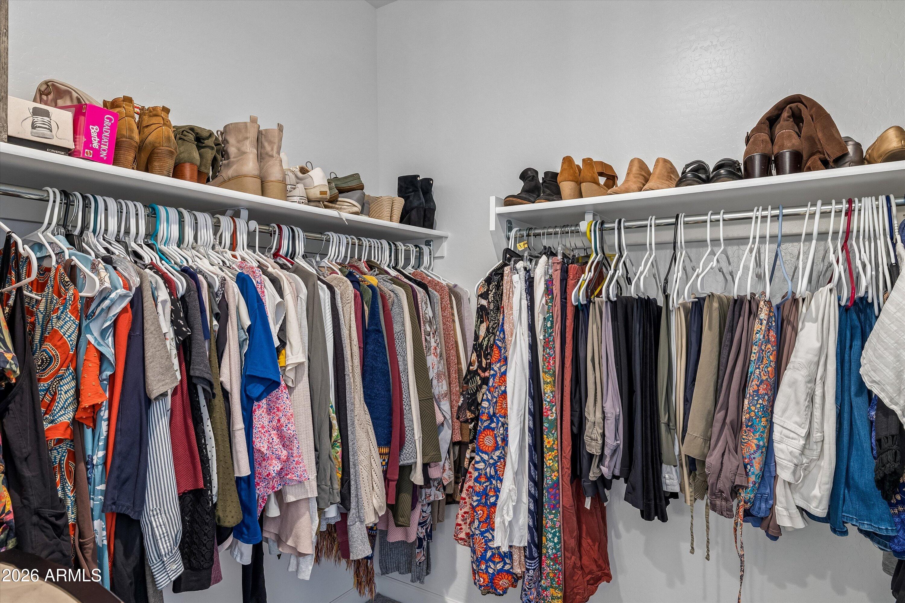 Walk-in closet with two clothing rails and shelves of shoes and boots.