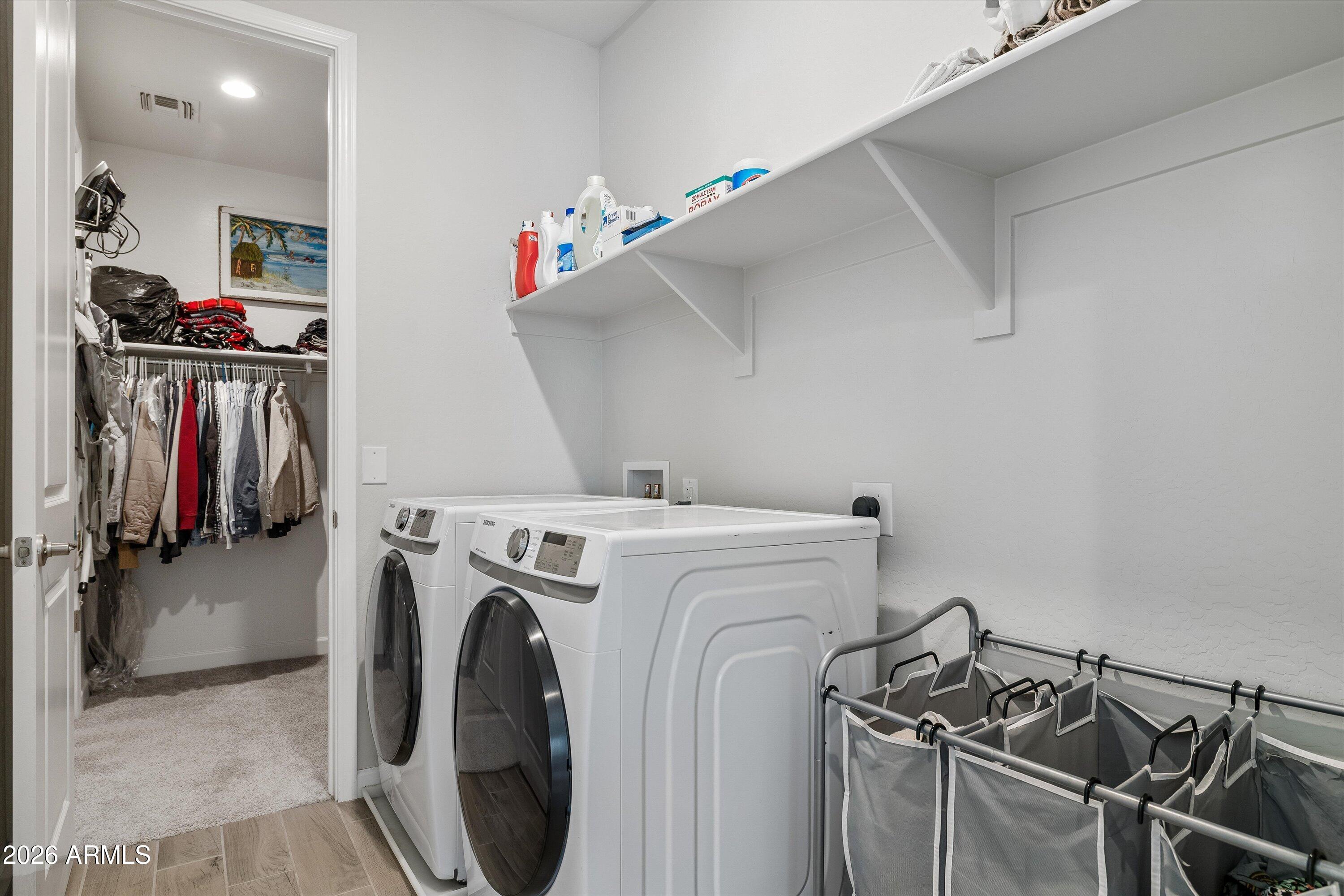 Laundry room with washer and dryer, overhead shelves, laundry sorter, and open closet.