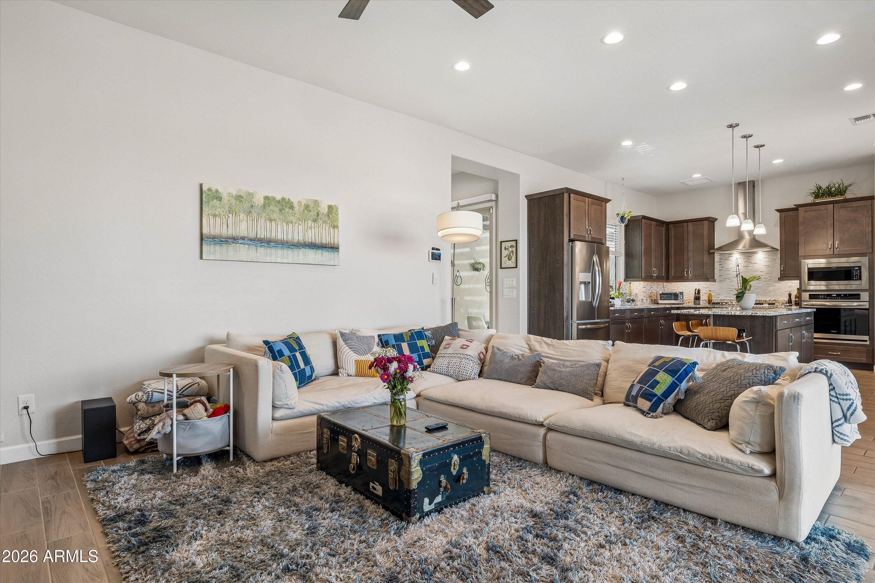 Open-plan living room and kitchen with a cream sectional, shag rug, and dark wood cabinetry.