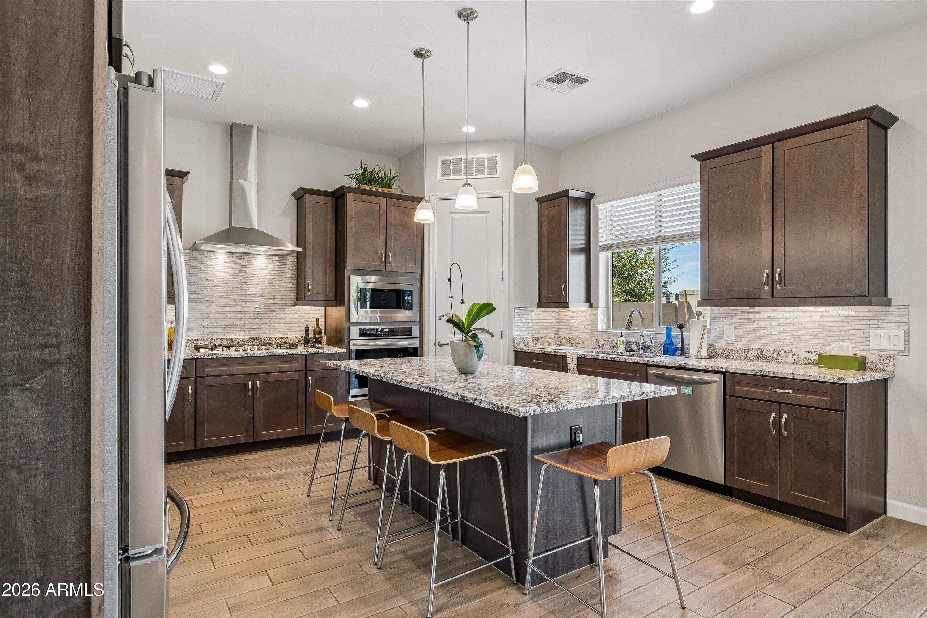 Kitchen with dark wood cabinets, granite island seating, and stainless steel appliances.