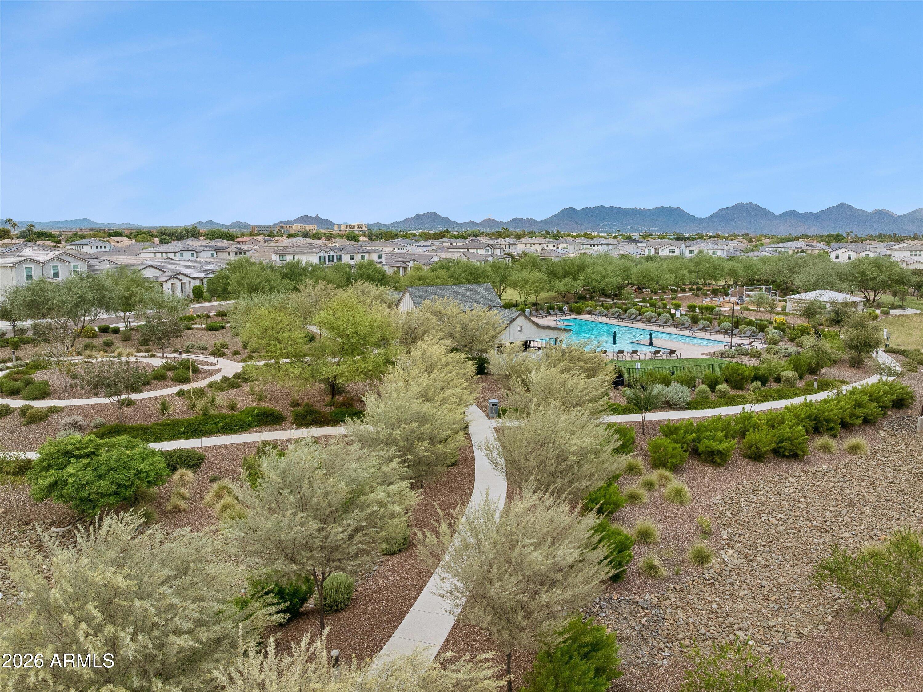 Community pool and landscaped walking paths with homes and mountains in the distance.