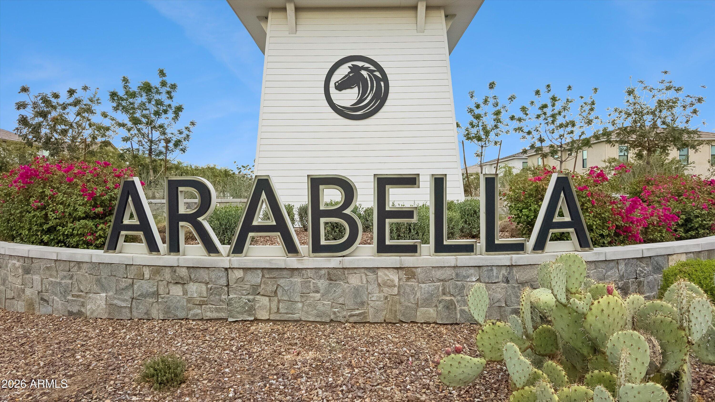 Arabella community entrance sign with a horse emblem, flowering shrubs, and desert landscaping.