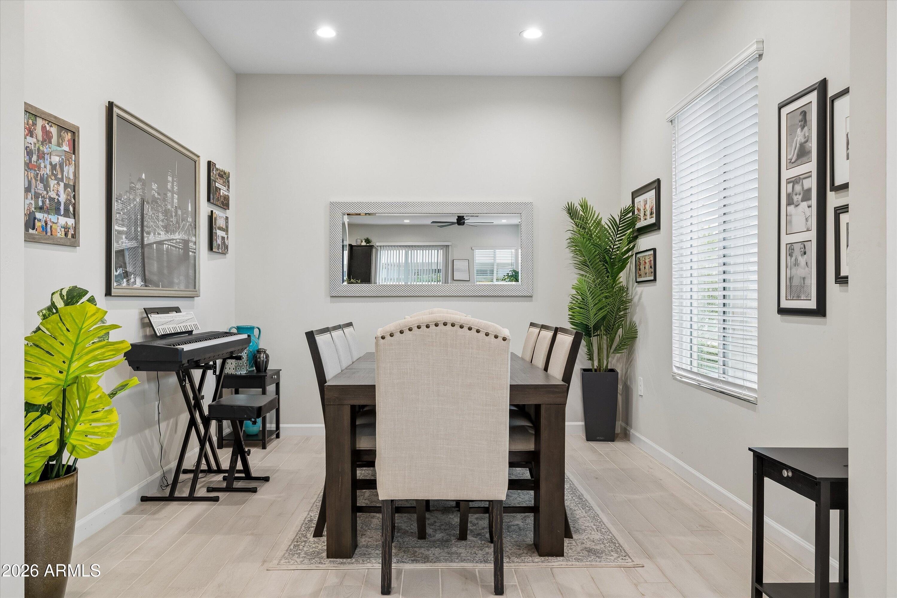 Dining room with a dark wood table, upholstered chairs, keyboard, and large mirror.