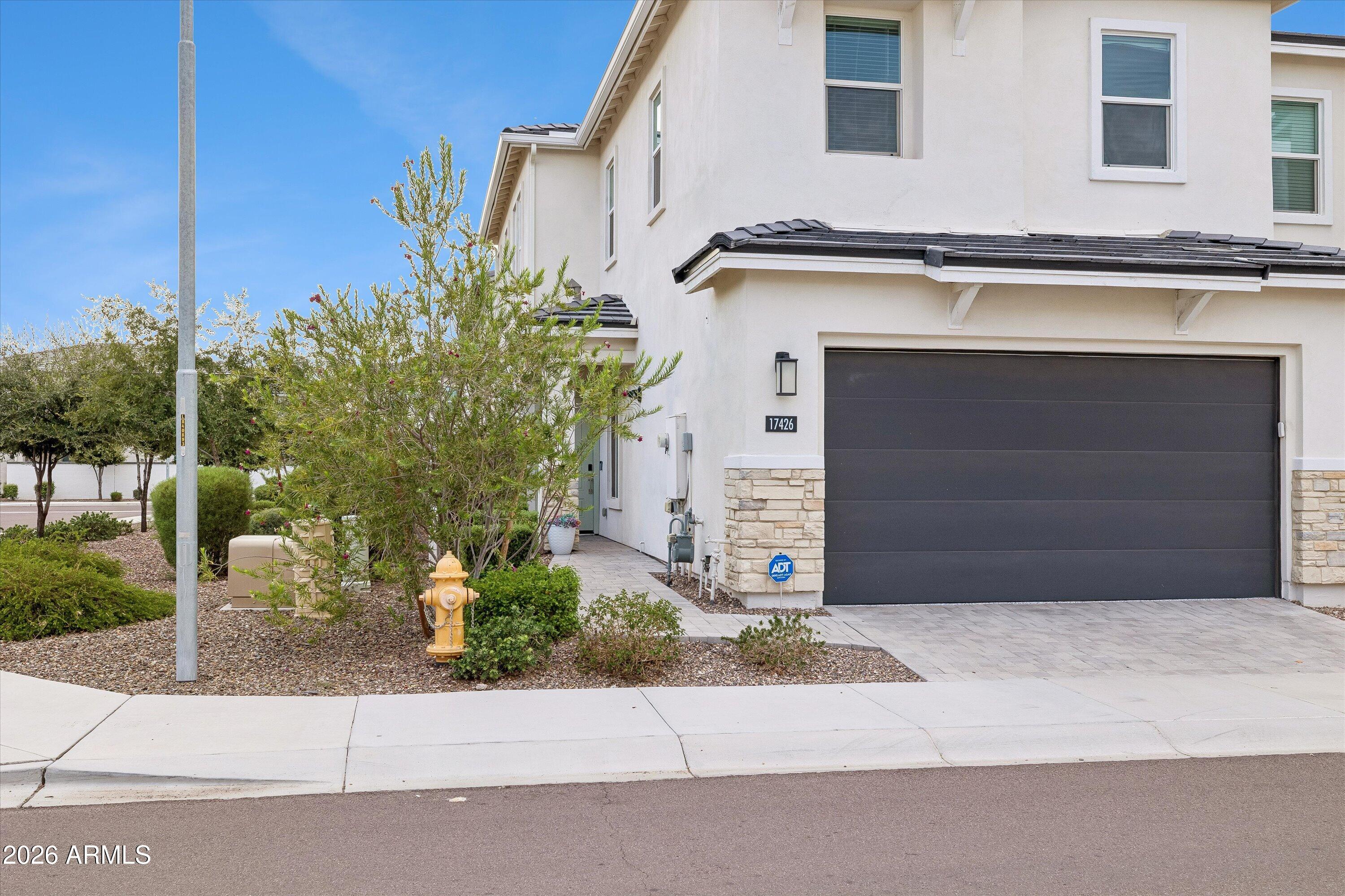 Two-story white home with a dark double garage, stone accents, and gravel landscaping.