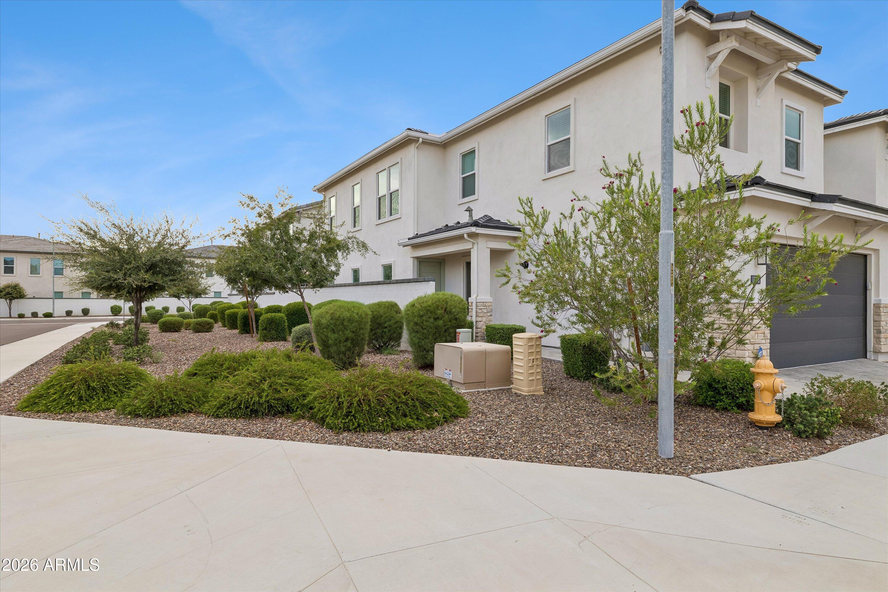 Two-story stucco home with a dark garage door and gravel landscaping.