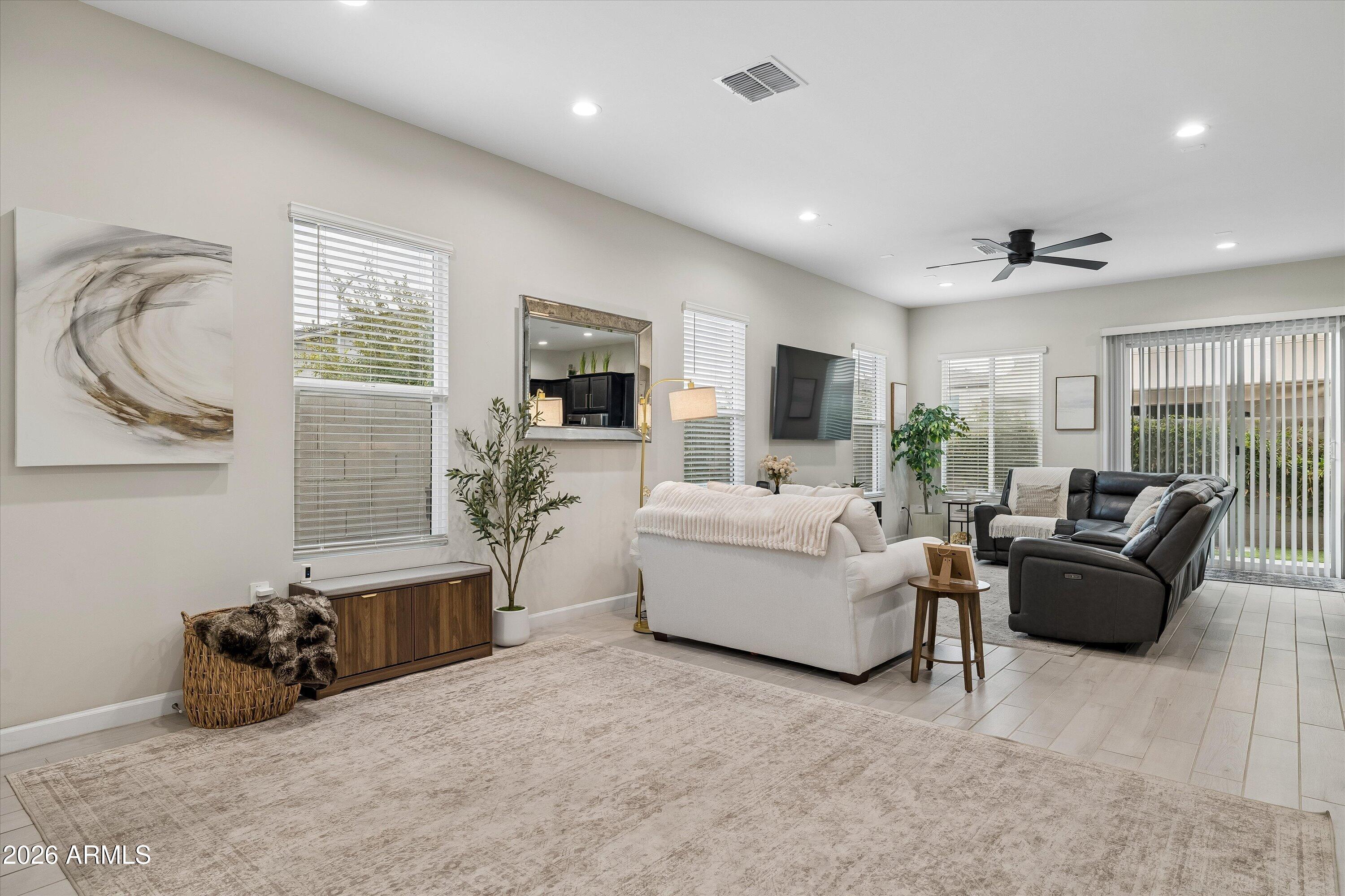 Staged living room with white and charcoal sofas, a large neutral rug, and sliding glass doors.