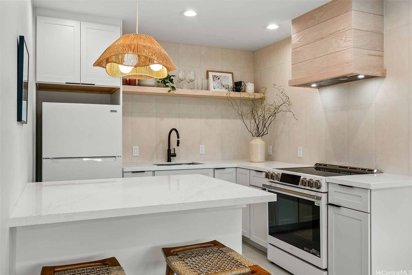 Modern white kitchen with a large marble-look island, stainless steel range, and woven pendant light.