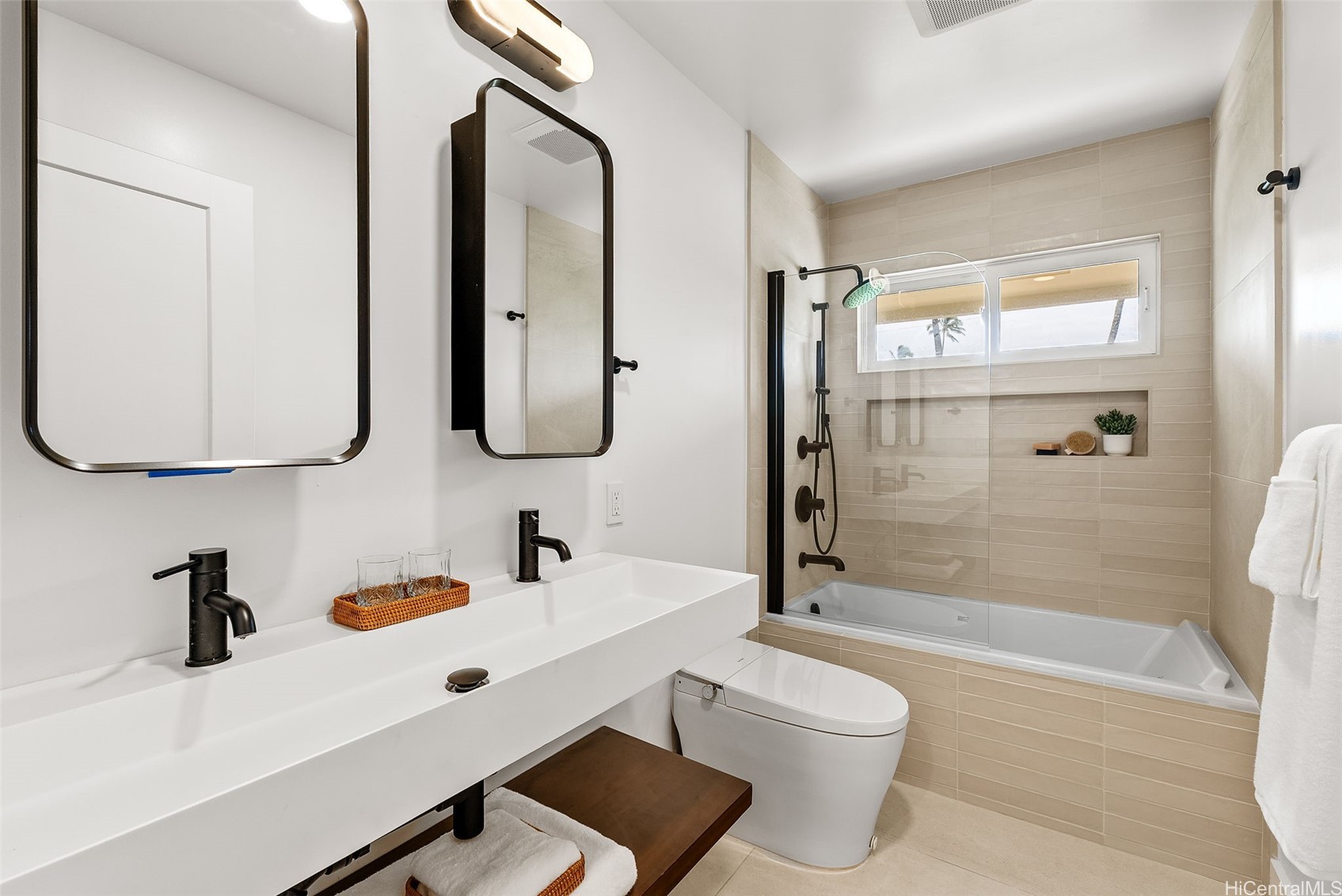 Bathroom with a long double vanity and glass-enclosed tub and shower.