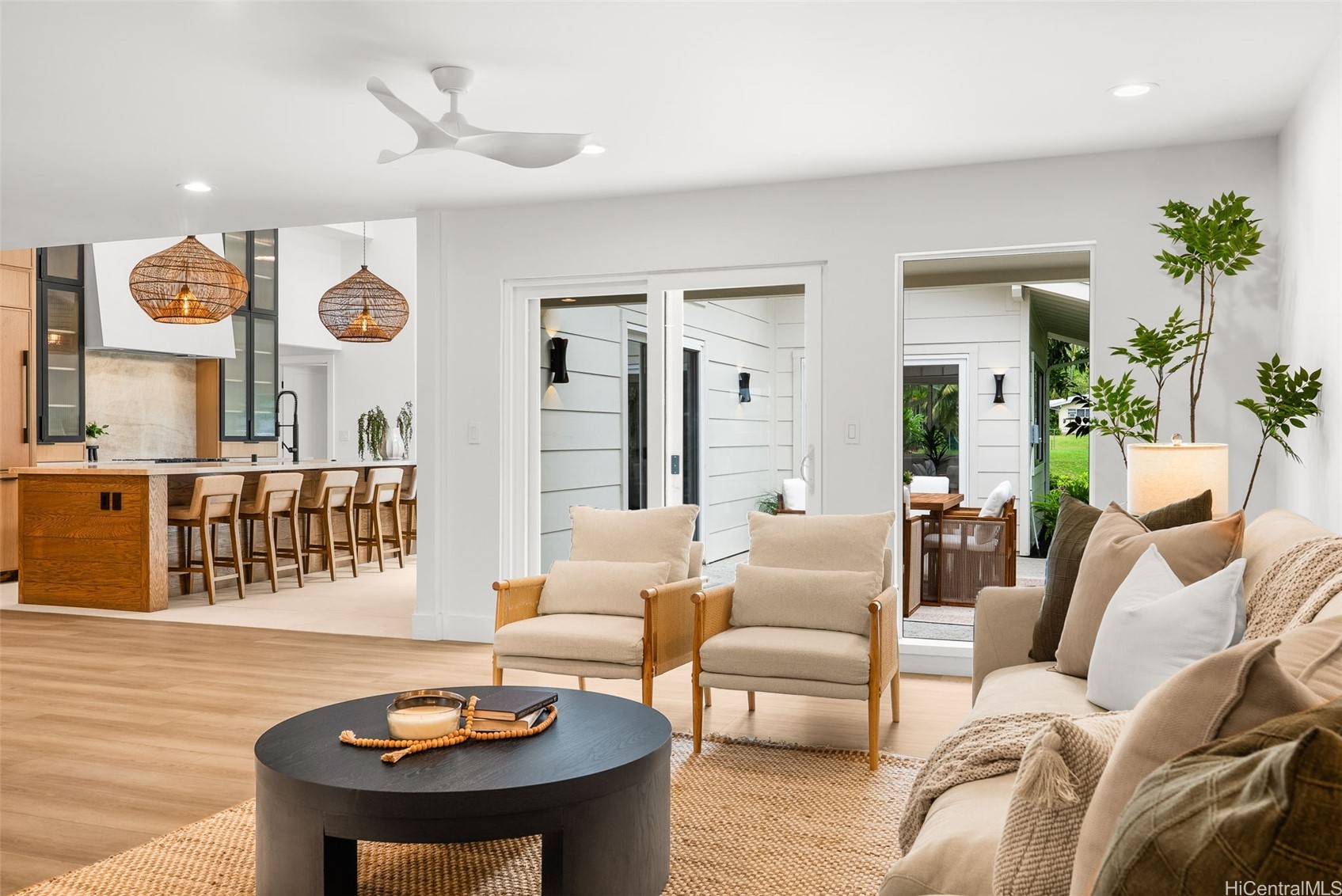 Open-plan living room and kitchen with wood island, woven pendant lights, and doors to a garden patio.