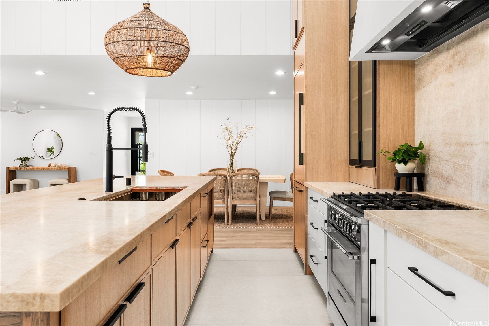 Modern kitchen with a pale stone island, light wood cabinetry, and stainless steel gas range.