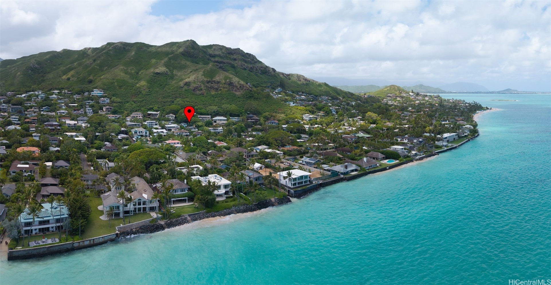 Aerial view of a Kailua coastal neighborhood, turquoise shoreline, green mountains, and a red location marker.