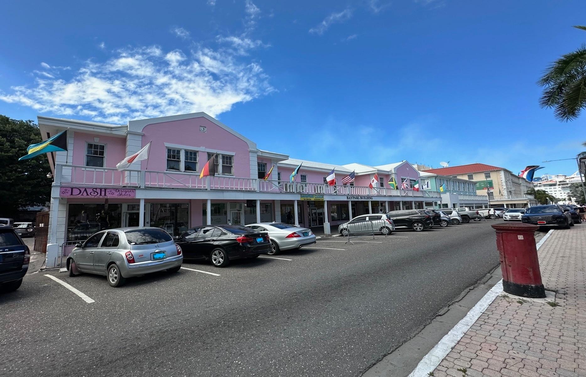 Pink two-story Bayparl Building storefront with international flags along Parliament Street.