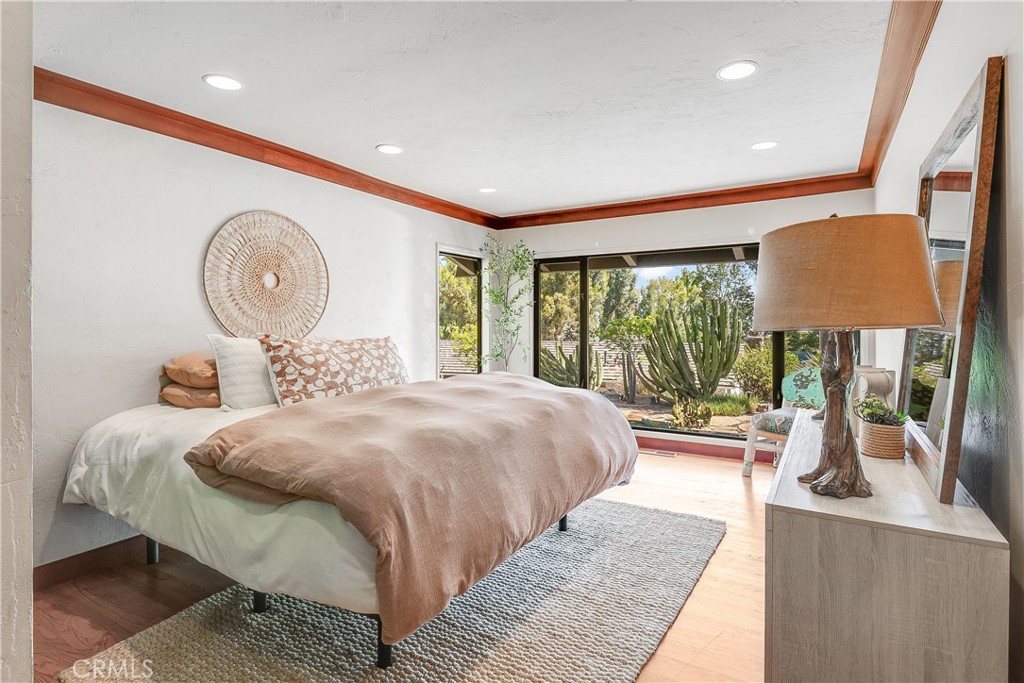 Furnished bedroom with large glass doors overlooking a garden of tall cacti.