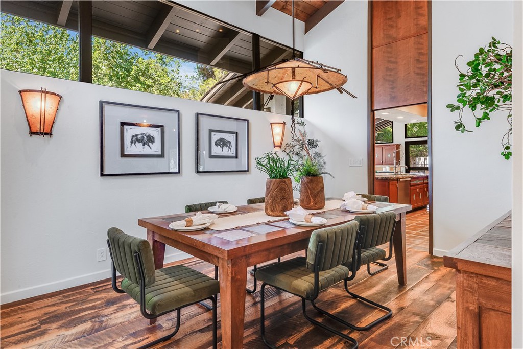Dining room with a set wooden table, olive-green chairs, and a large pendant light.