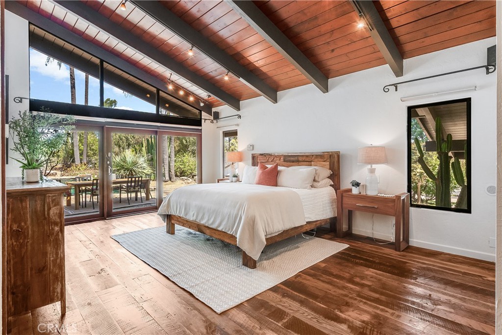 Primary bedroom with a king bed beneath a vaulted wood ceiling and sliding doors to a patio.