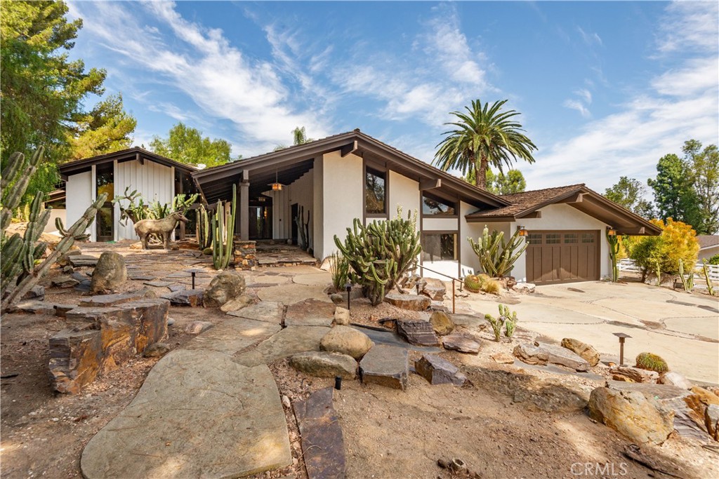 Home with angular rooflines, attached garage, and a rocky cactus garden.