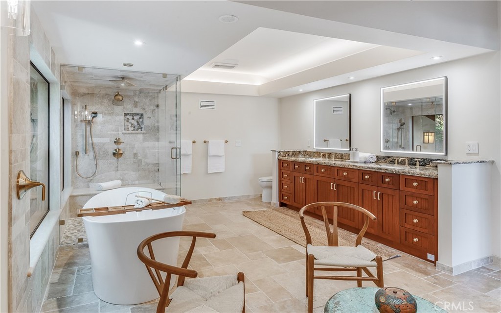 Spacious bathroom with a freestanding tub, glass shower, and long wood double vanity.