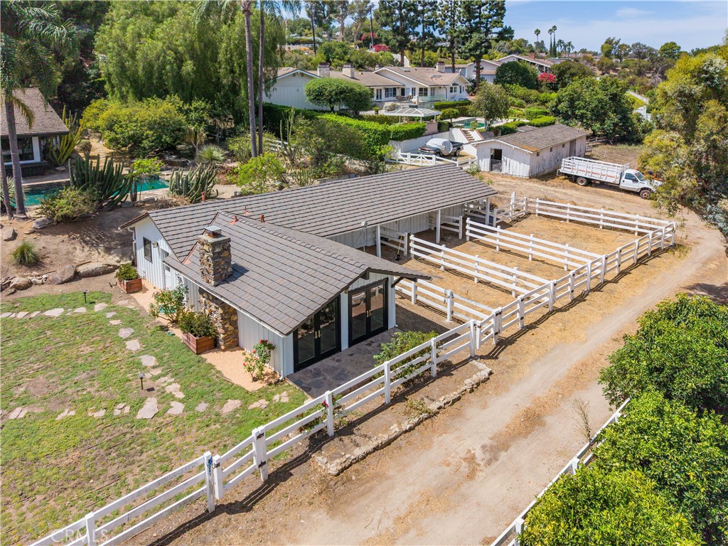 Aerial view of a single-story home with a white-fenced paddock and landscaped grounds.