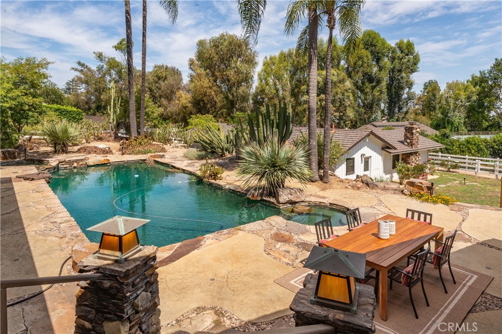 Backyard pool and stone patio with outdoor dining area and a small detached outbuilding.