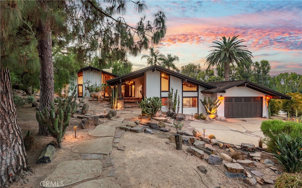 Contemporary home with a two-car garage, cactus landscaping, and a colorful dusk sky.