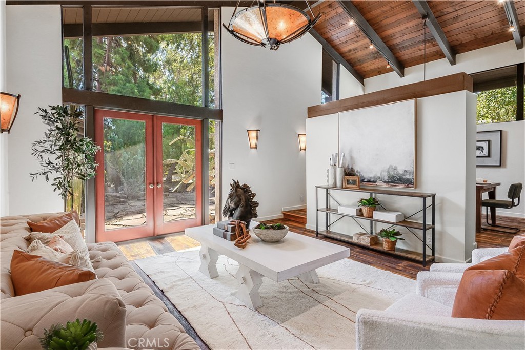 Vaulted living room with tall glass doors, a wood ceiling, and neutral seating.