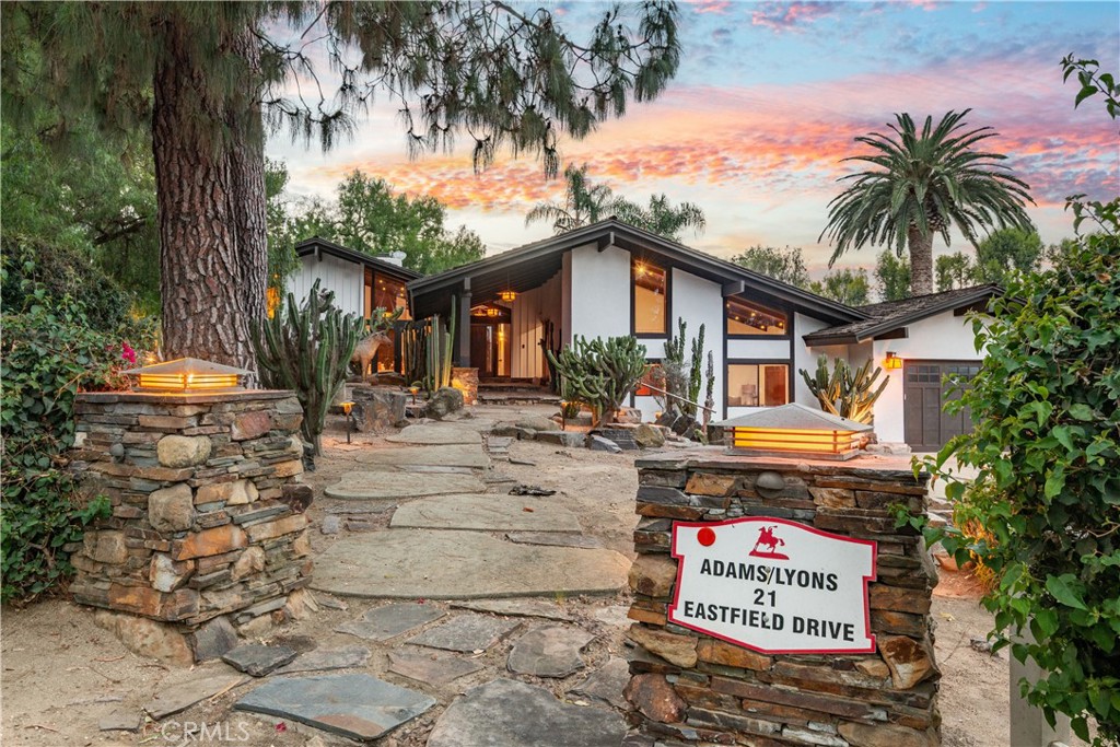 Modern home at dusk with a stone entry walkway and an Adams/Lyons sign.