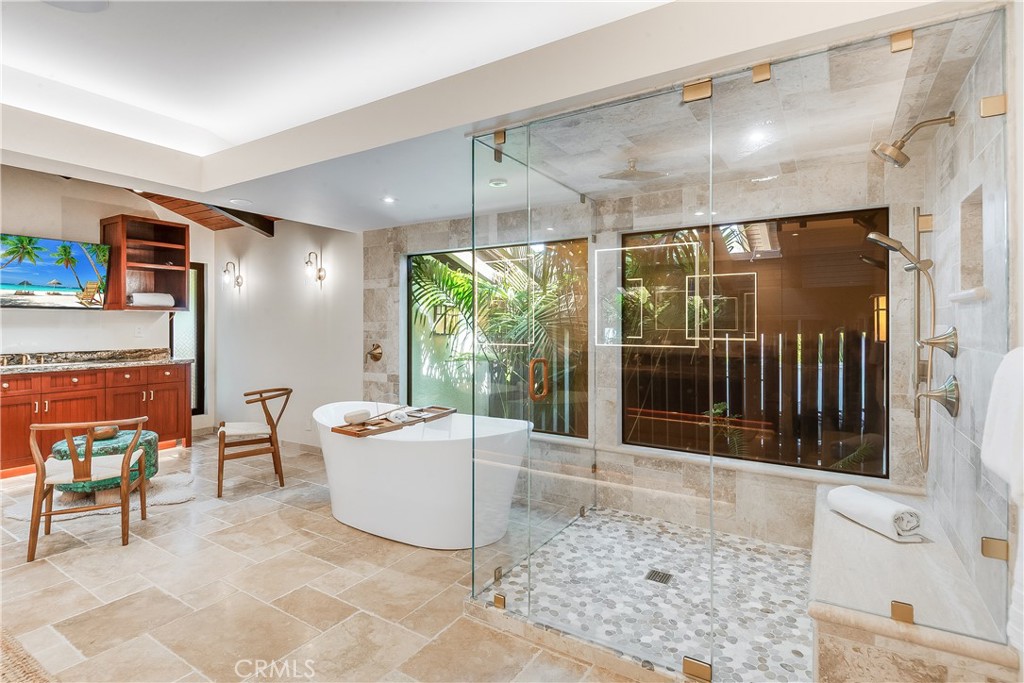 Bathroom with freestanding tub, glass shower with pebble floor, and wood vanity.