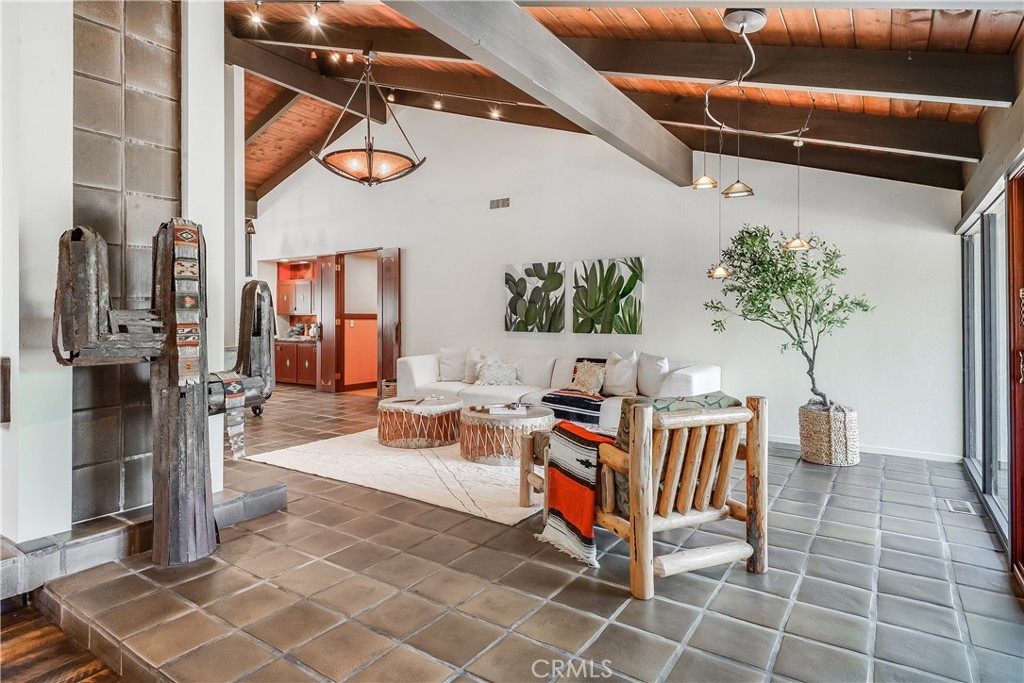 Living room with exposed wood beams, tiled floors, and rustic seating.