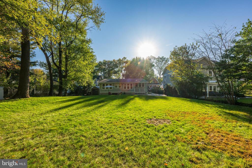 House seen across a broad backyard lawn framed by mature trees.