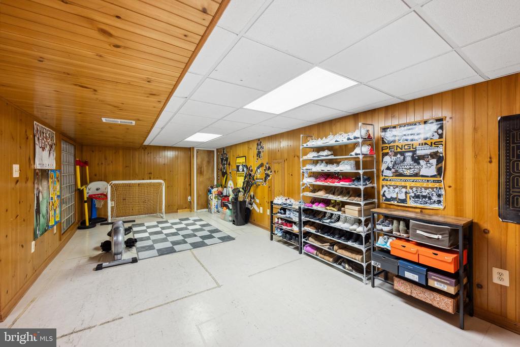 Recreation room with wood paneling, hockey memorabilia, shoe racks, and a small goal.