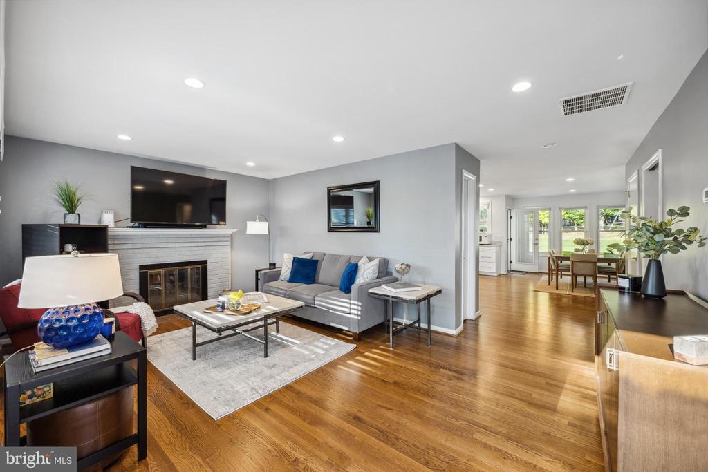 Open-plan living room with a white fireplace and gray sofa leading to a dining area by glass doors.