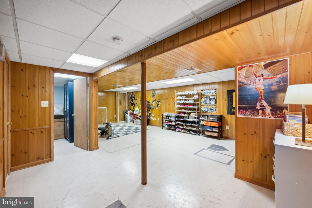 Basement recreation room with wood paneling, an exercise bike, sports memorabilia, and open shelving.