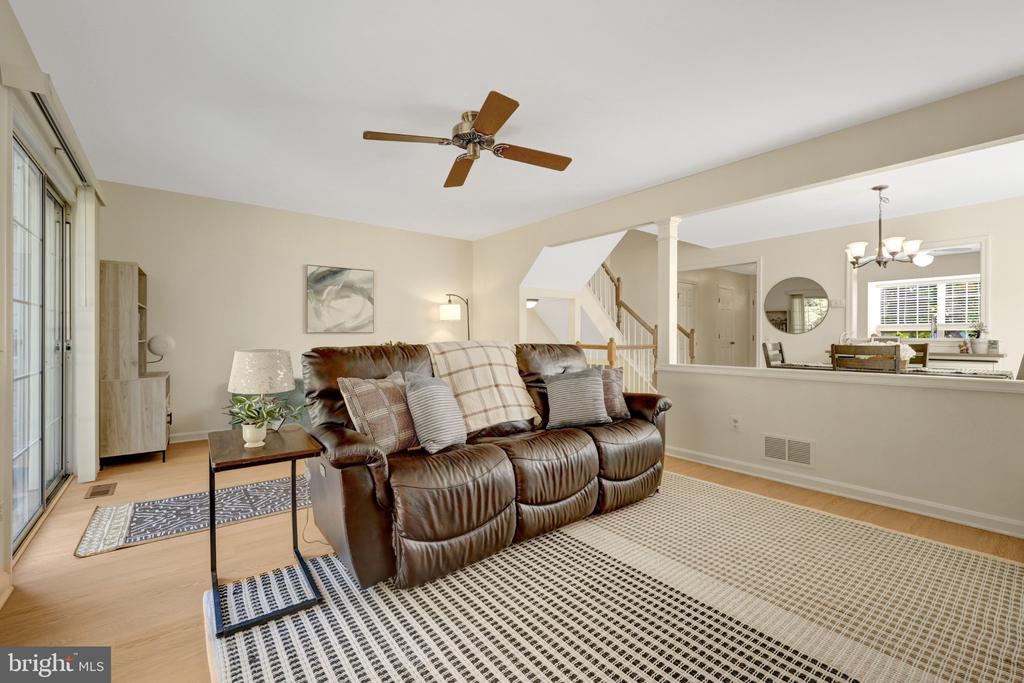 Living room with a brown leather sofa, patterned rug, and sliding glass doors.
