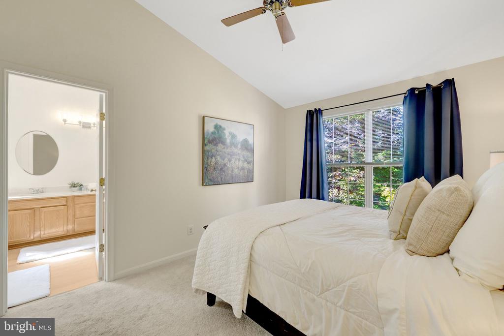 Bedroom with a white quilted bed, dark blue curtains, and an open doorway to the bathroom.