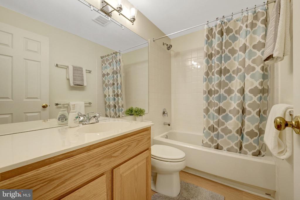 Bathroom with a wood vanity, bathtub, and patterned shower curtain.