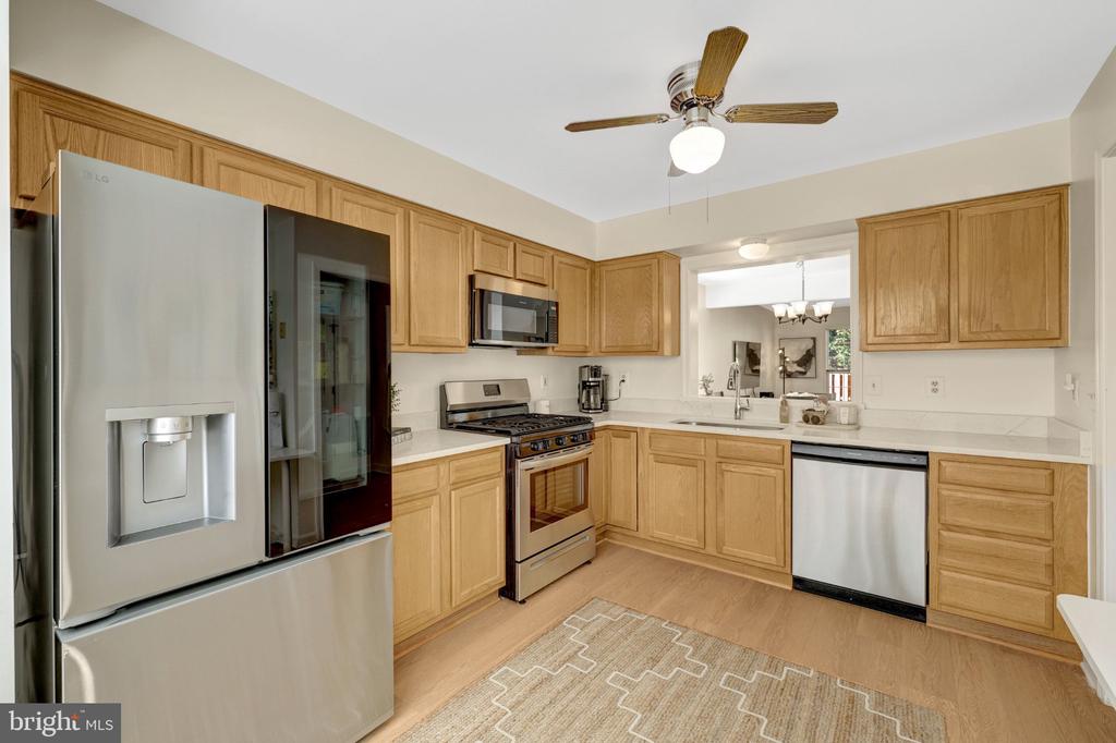Kitchen with light wood cabinetry, stainless steel appliances, and a patterned rug.