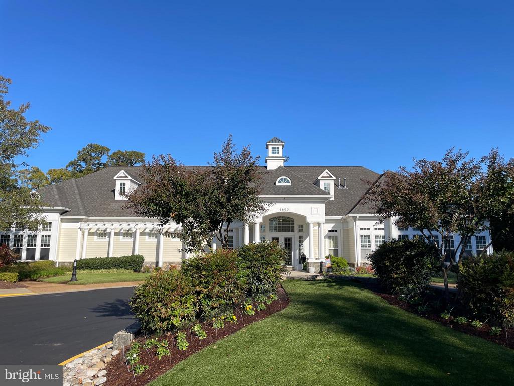 Pale yellow building with a columned entrance, landscaped grounds, and paved driveway.