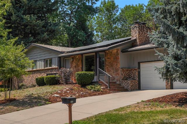 Ranch-style house with a stone-and-brick facade, attached garage, and mature trees.
