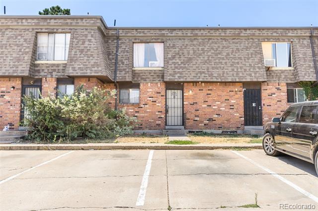 Two-story brick apartment building with a stone-pattern upper facade and parking spaces in front.